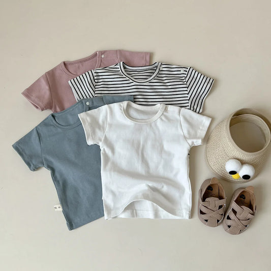 Collection of children's clothing including t-shirts and shoes on a neutral background