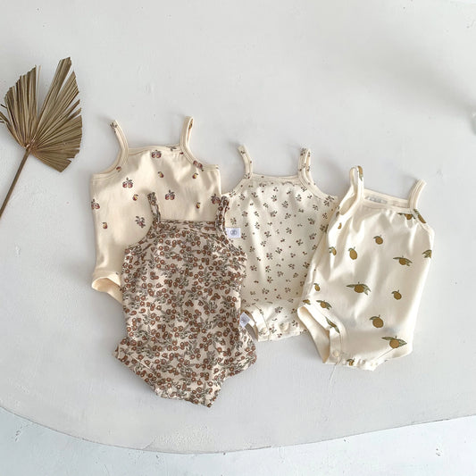 Four baby rompers with floral and animal prints on a white surface.