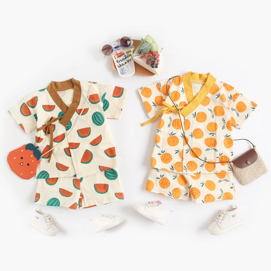 Two children's outfits with fruit patterns on a white background